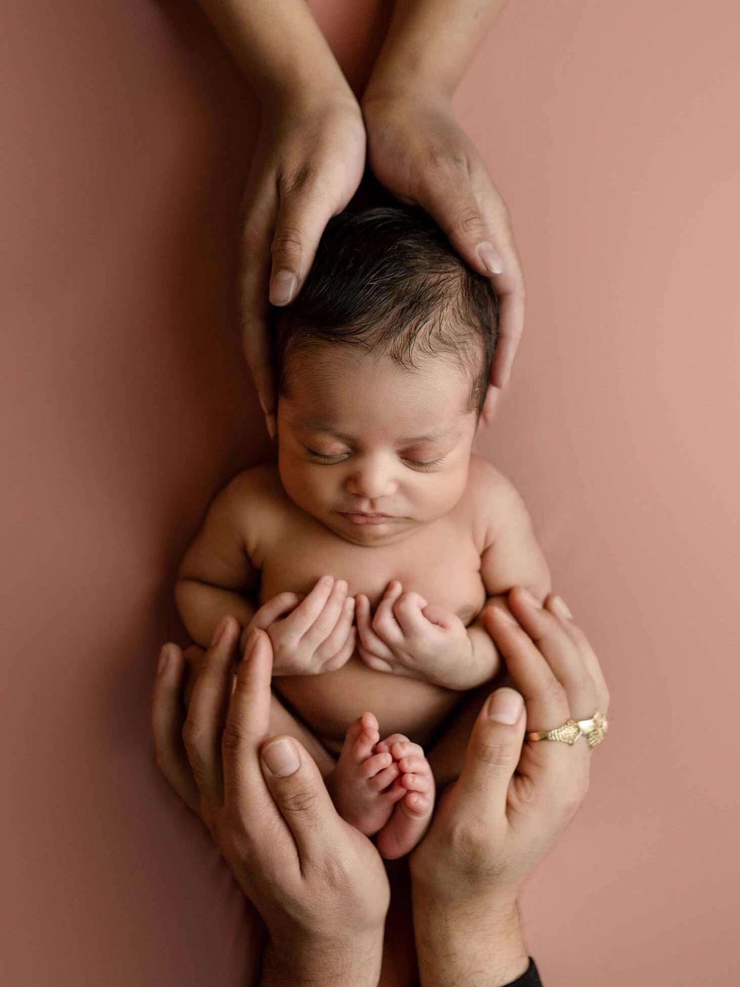 Calgary newborn photography, baby girl sleeping in mom and dad hands