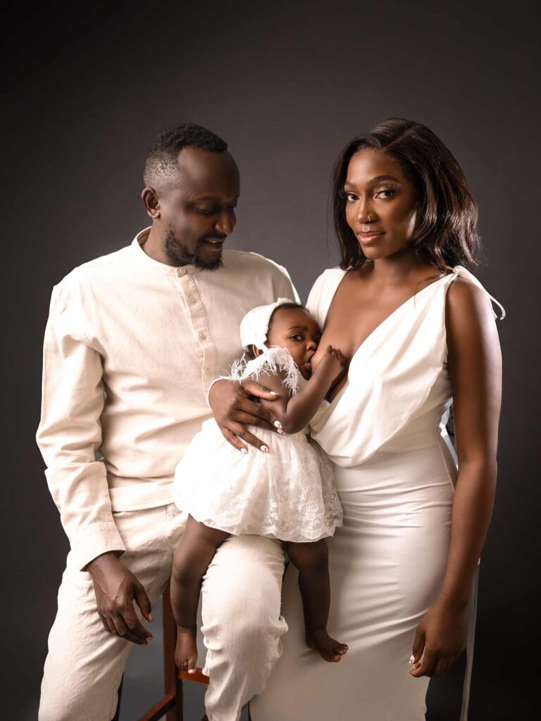 Family of three in Calgary posing for a photography photoshoot, mom breastfeeding her baby