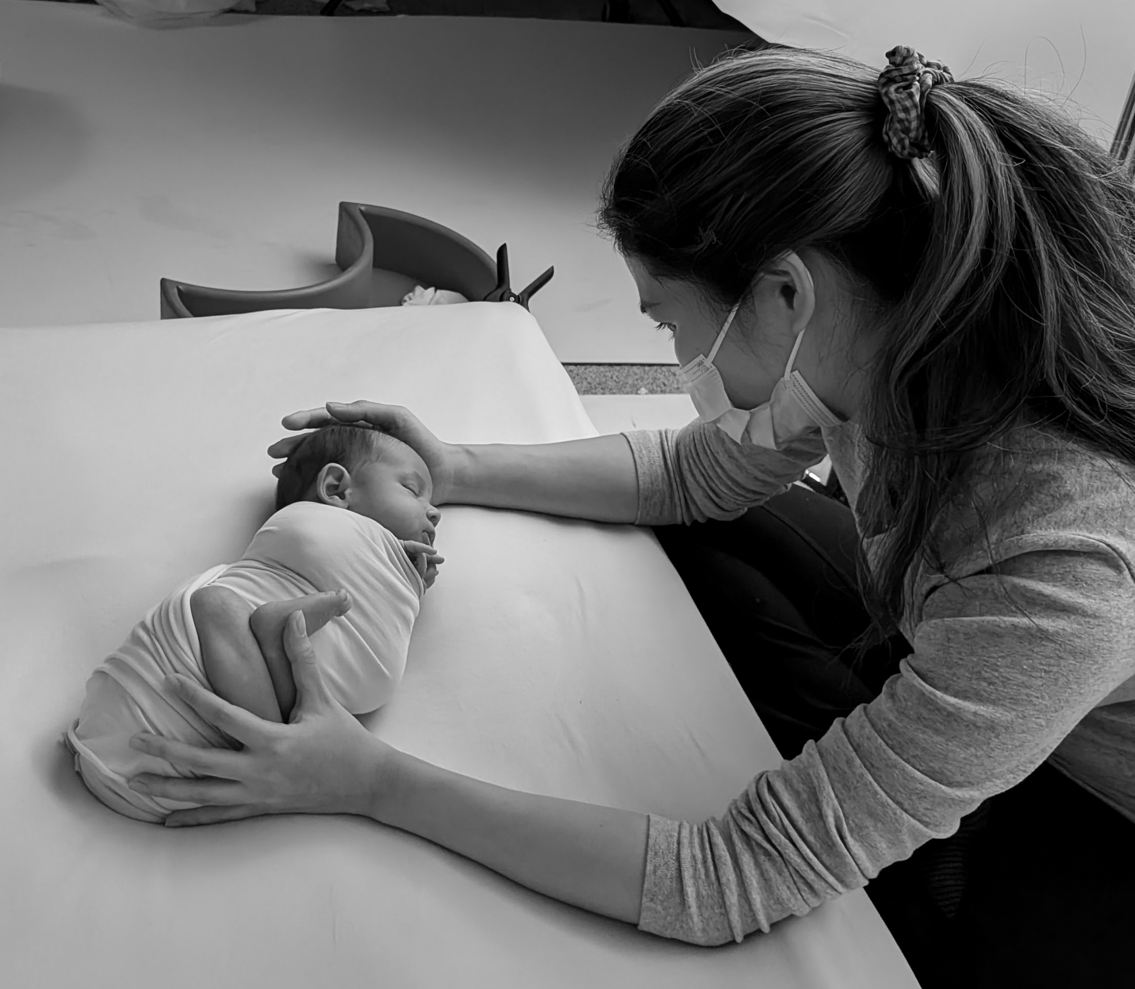 Newborn photographer in Calagary, photographer wearing mask pose newborn baby in a safe surface