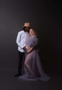 Expectant couple in elegant outfits posing for a maternity photoshoot in Calgary photography studio