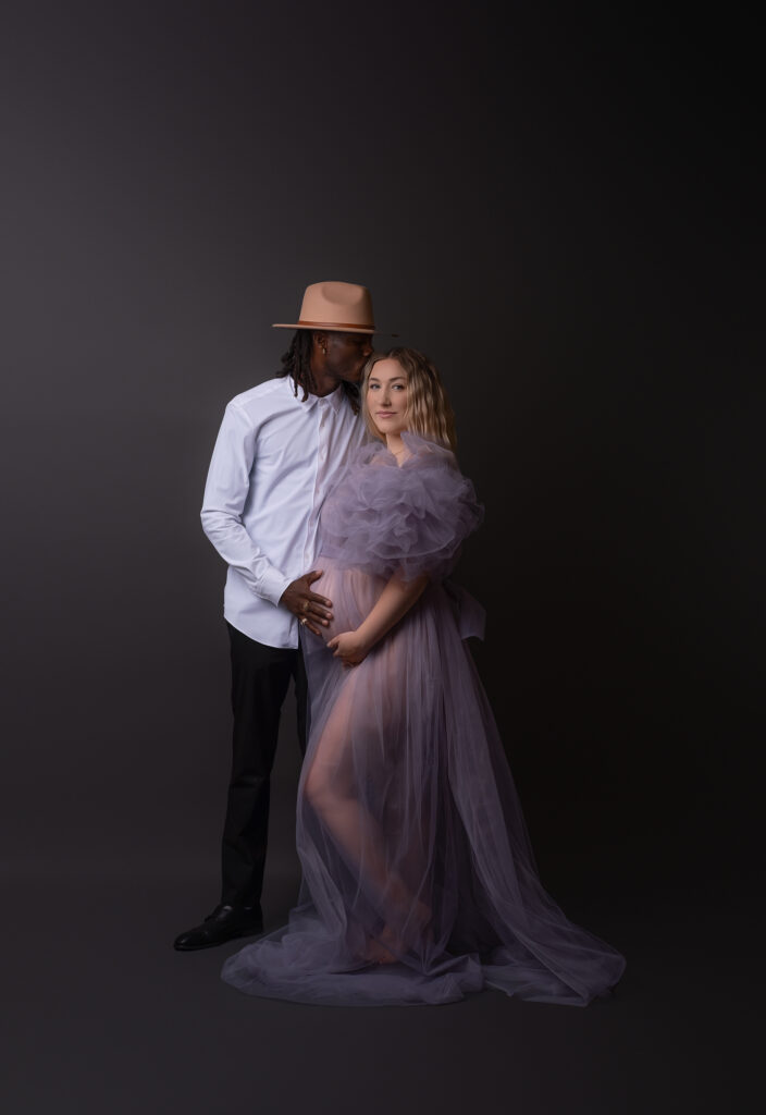 Expectant couple in elegant outfits posing for a maternity photoshoot in Calgary photography studio
