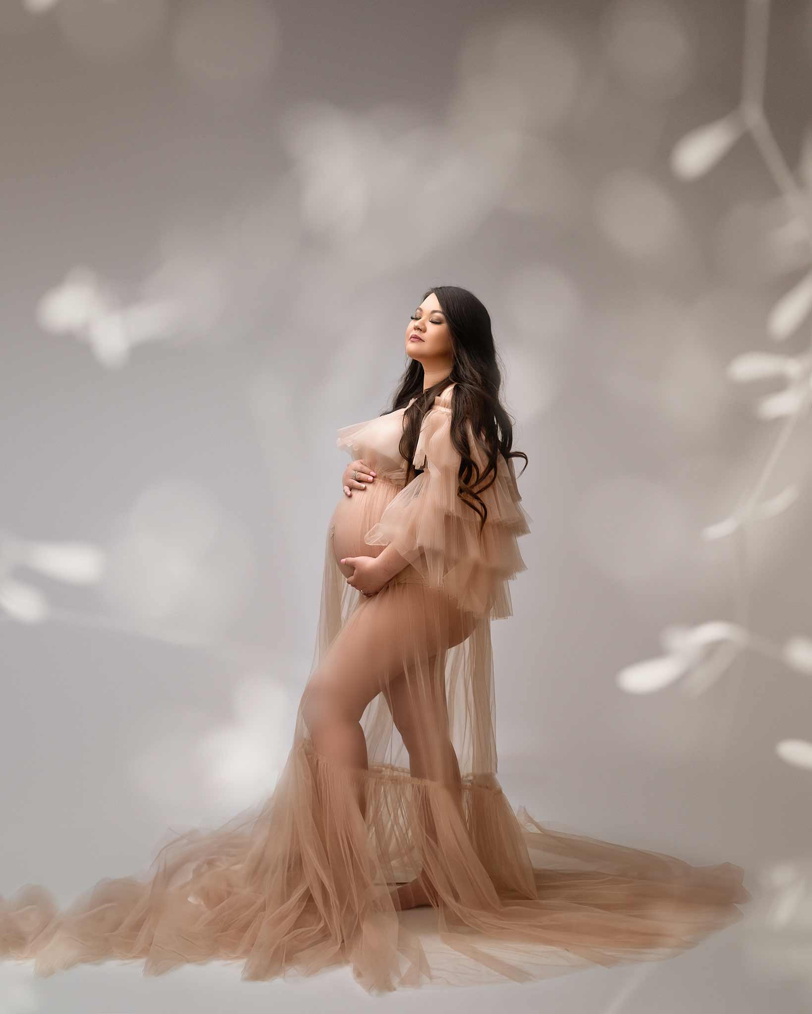 Pregnant woman wearing a long gown at Tiara Tran Photography studio in Calgary