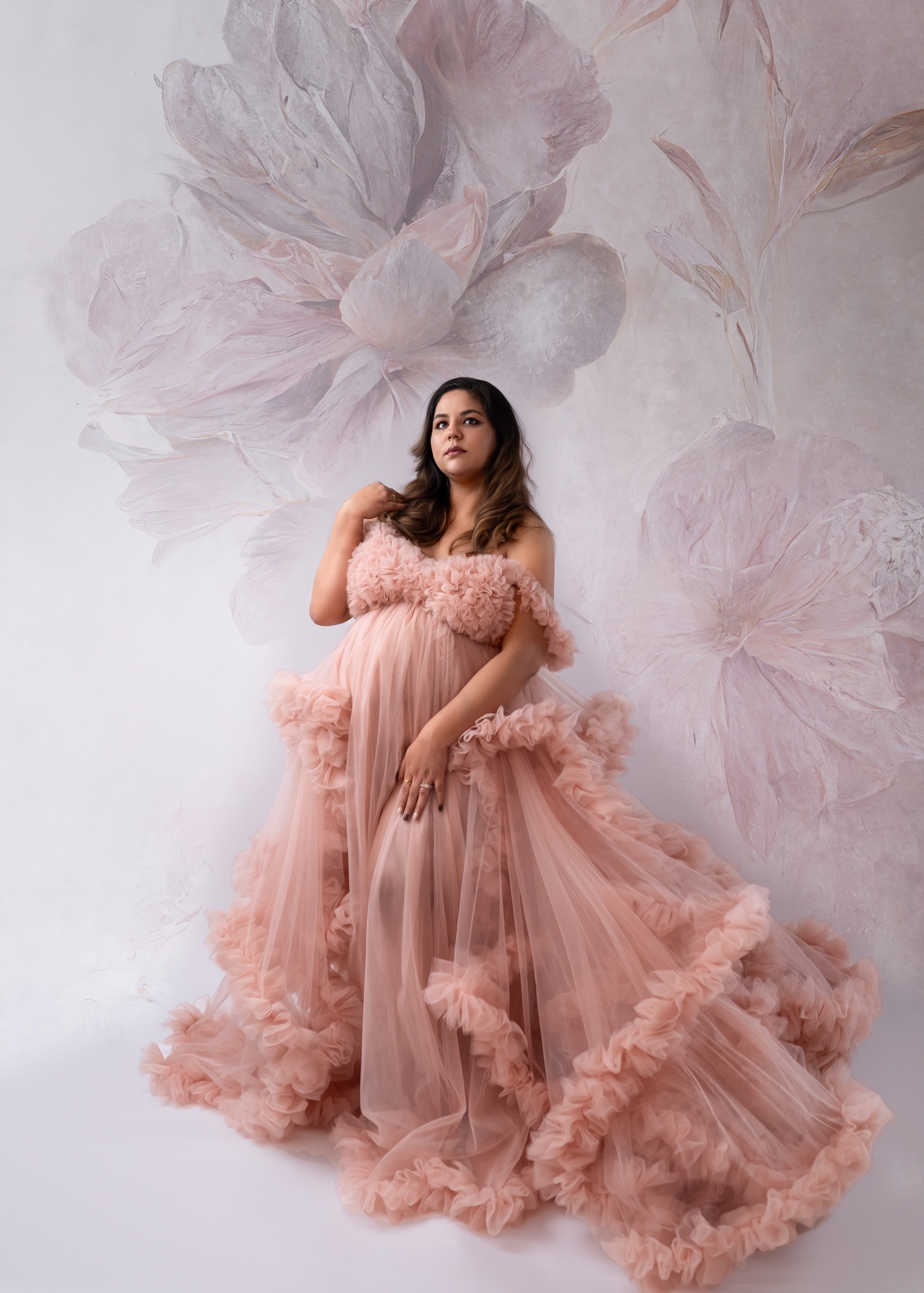 Maternity photography in Calgary studio, pregnant woman in a pink gown in front of a floral background
