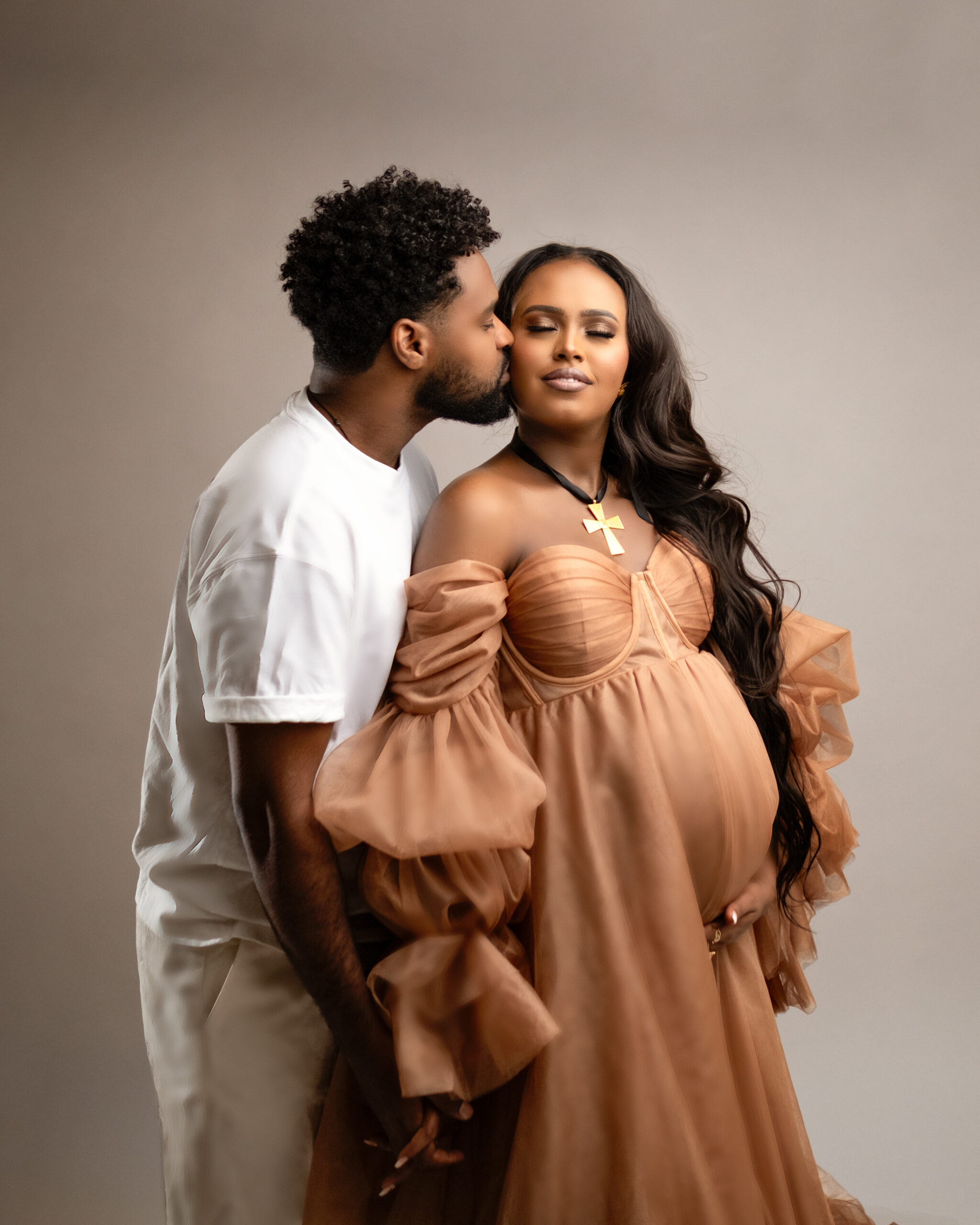 Husband kissing wife for maternity photoshoot in a studio, Calgary