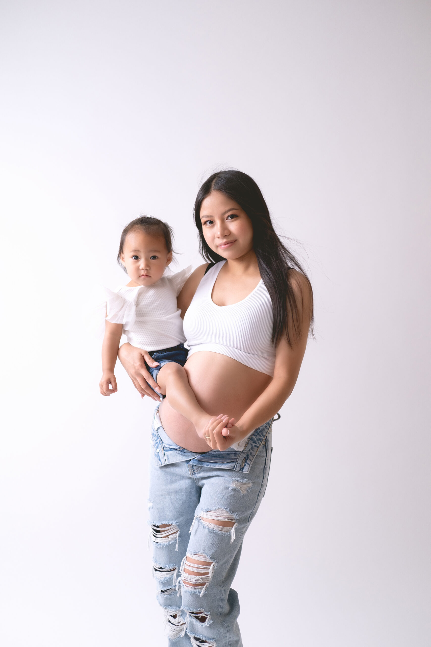 pregnant woman holding a young toddler for a photoshoot in Calgary