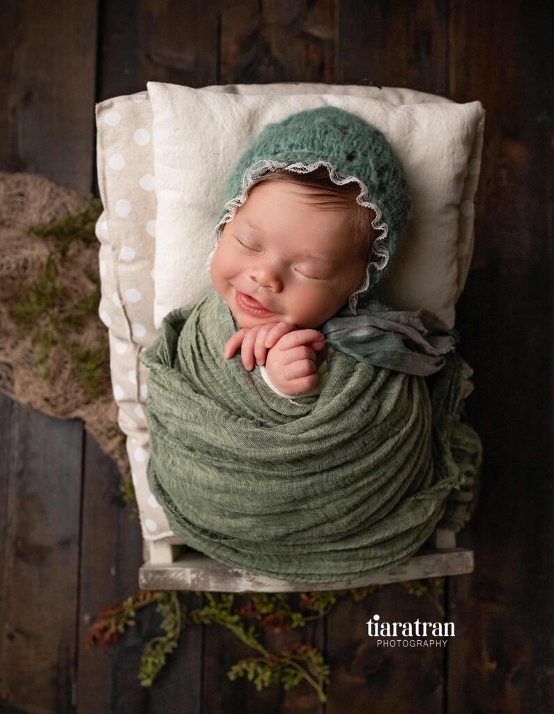 Newborn baby girl smiling for photoshoot - Tiara Tran Photography in Calgary