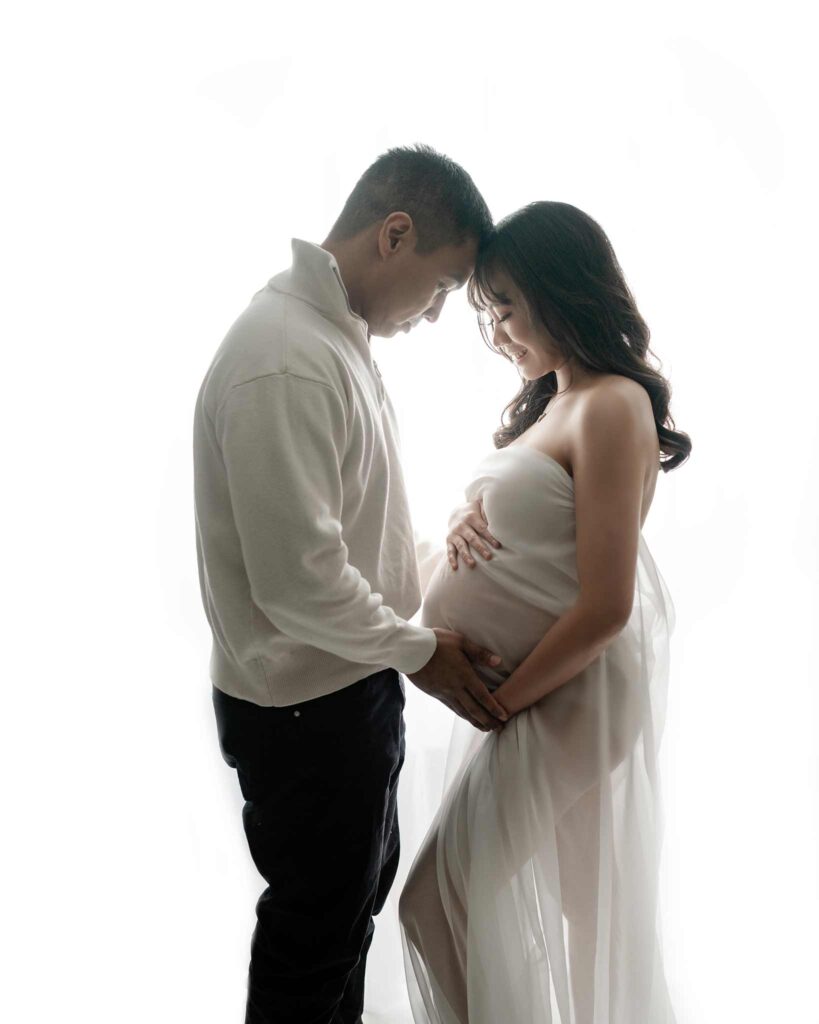 Couple maternity posing for a photoshoot in Calgary photography studio