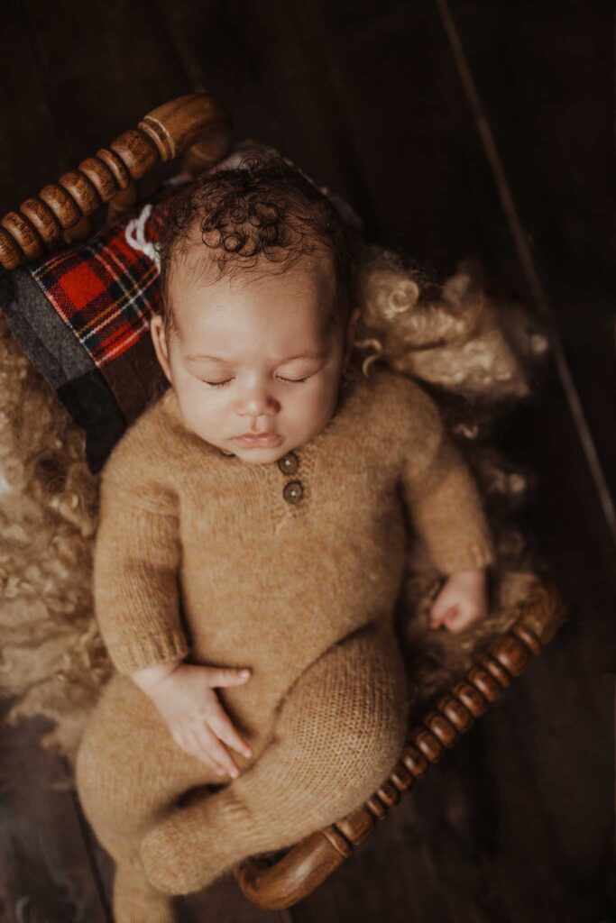 Newborn baby sleeping in a tiny bed for photoshoot