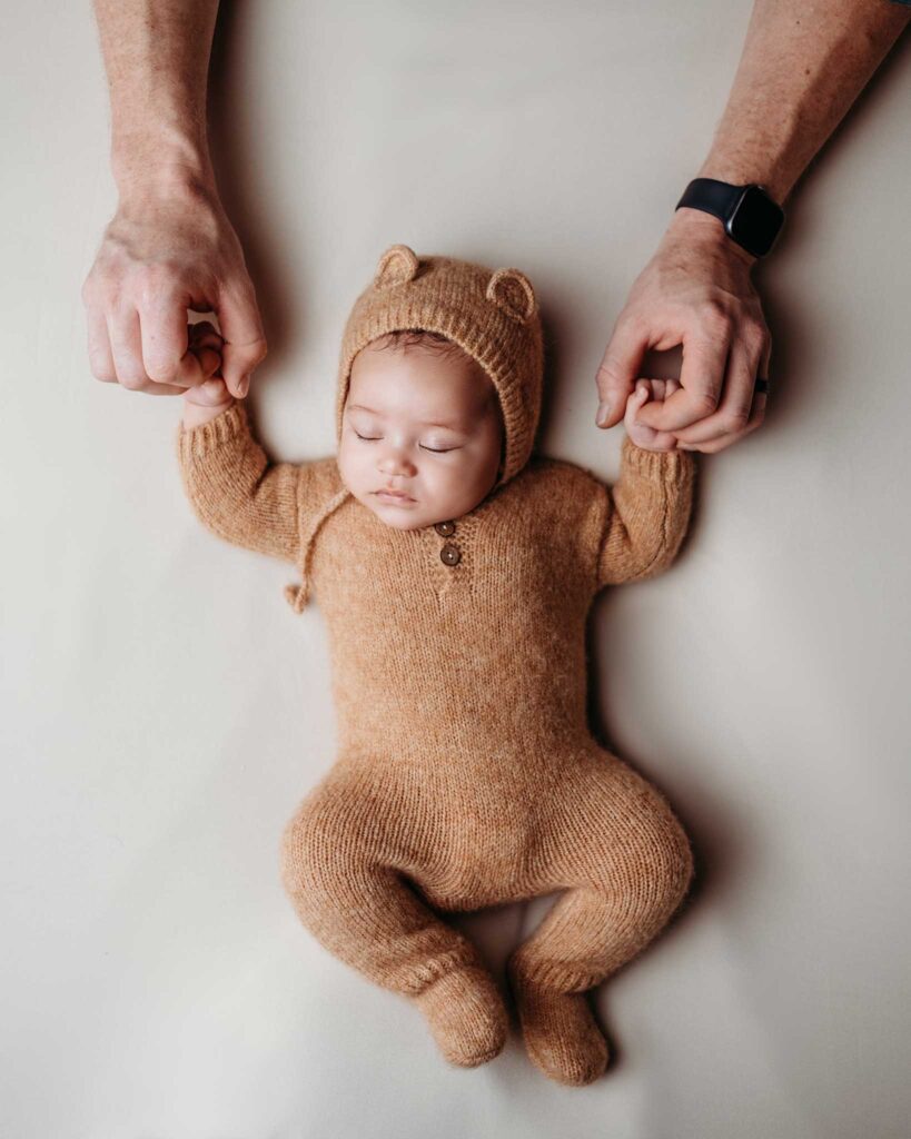 Baby Beau sleeping soundly holding daddy's hand